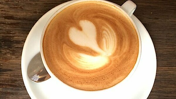 Tasse mit Cappuccino und in den Schaum gezeichneter Herz-Blüte