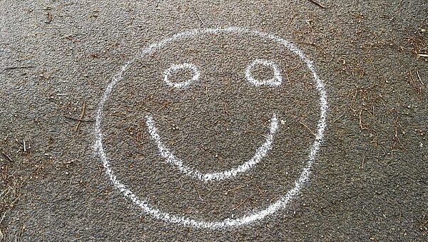 gemalter Kreidesmiley mit Kreide auf den Boden gemalter Smiley