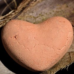 Herz geformt aus Ton auf Holz und Stroh