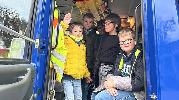 Kommunionkinder sitzen im Führerhaus des THW-LKW