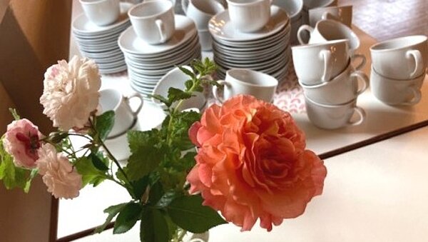 bereitgestellte Kaffeetassen mit Rosenstrauß