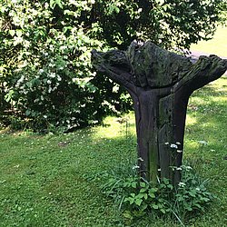 In einen Baumstamm geschnitzte Jesusfigur am Kreuz 